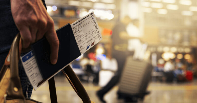 空港で航空券とパスポートとカバンを右手に持つ人の手元アップ