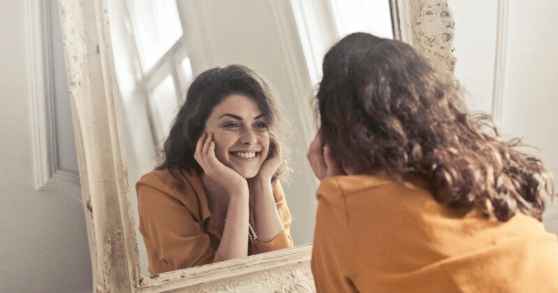 鏡に向かってほほ笑む女性